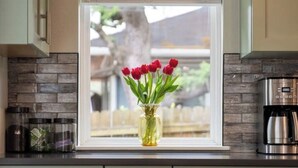 Una finestra della cucina con un vaso di tulipani rossi.