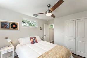 A bedroom with a bed, a nightstand, a ceiling fan, a window, and a door. - Great Location - Downtown, SOCO, Zilker Park, ACL Festival and SEC Football! (Austin)