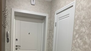 Un couloir avec une porte blanche, un porte-manteau et une petite table en bois.