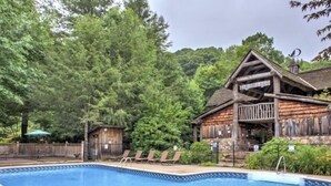Eine rustikale Holzhütte mit Pool und Liegestühlen.