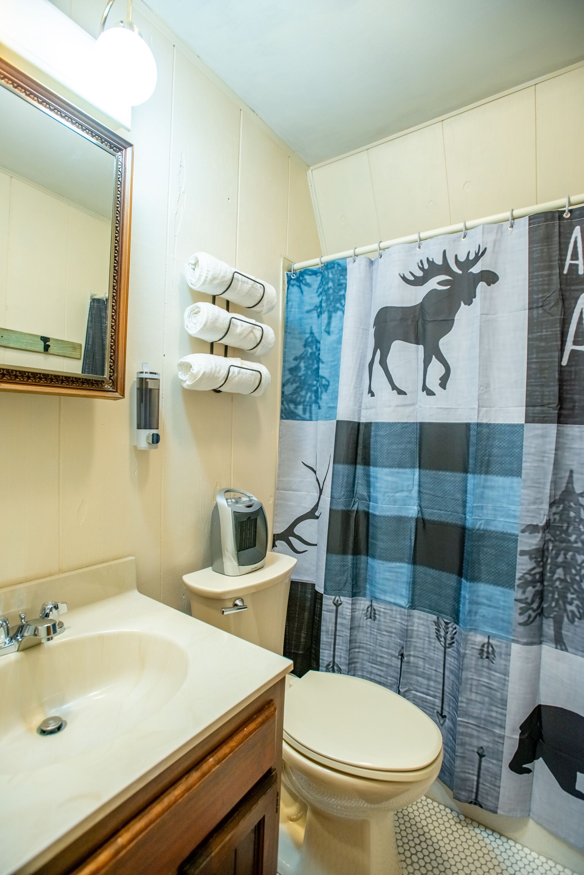 Ein Badezimmer mit großem Spiegel, Toilette, Waschbecken und Duschvorhang mit Tiermotiven.