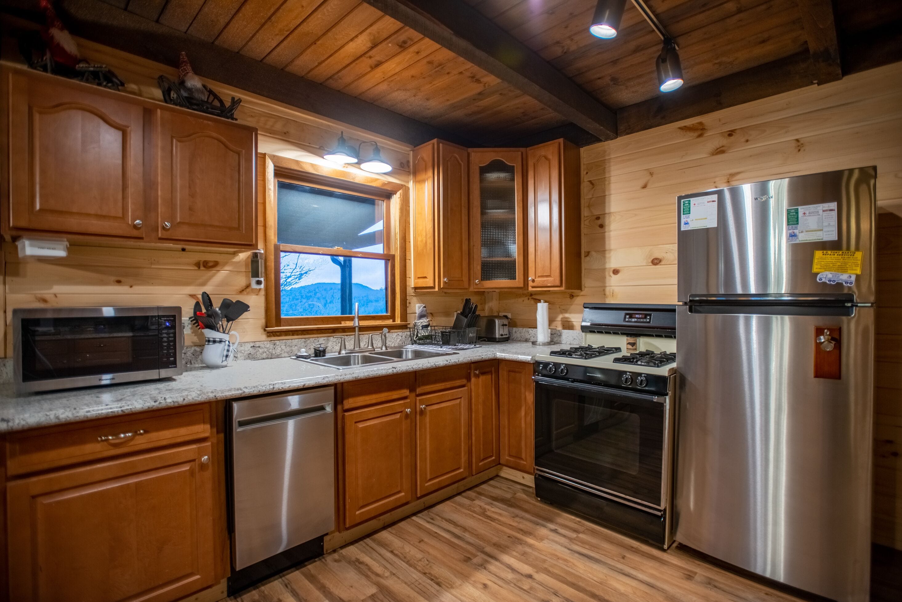 Une cuisine moderne avec des meubles en bois, des appareils électroménagers en acier inoxydable et une grande fenêtre.