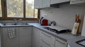 A modern kitchen with a sink, stove, and cabinets. - Comfortable apartment just minutes from the city (Su Planu)