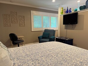 A bedroom with a bed, a chair, a desk, a television, and decorative items on a shelf. - Sarasota Cozy & Clean, Near #1 Beach Siesta in SouthGate Neighborhood (Sarasota)