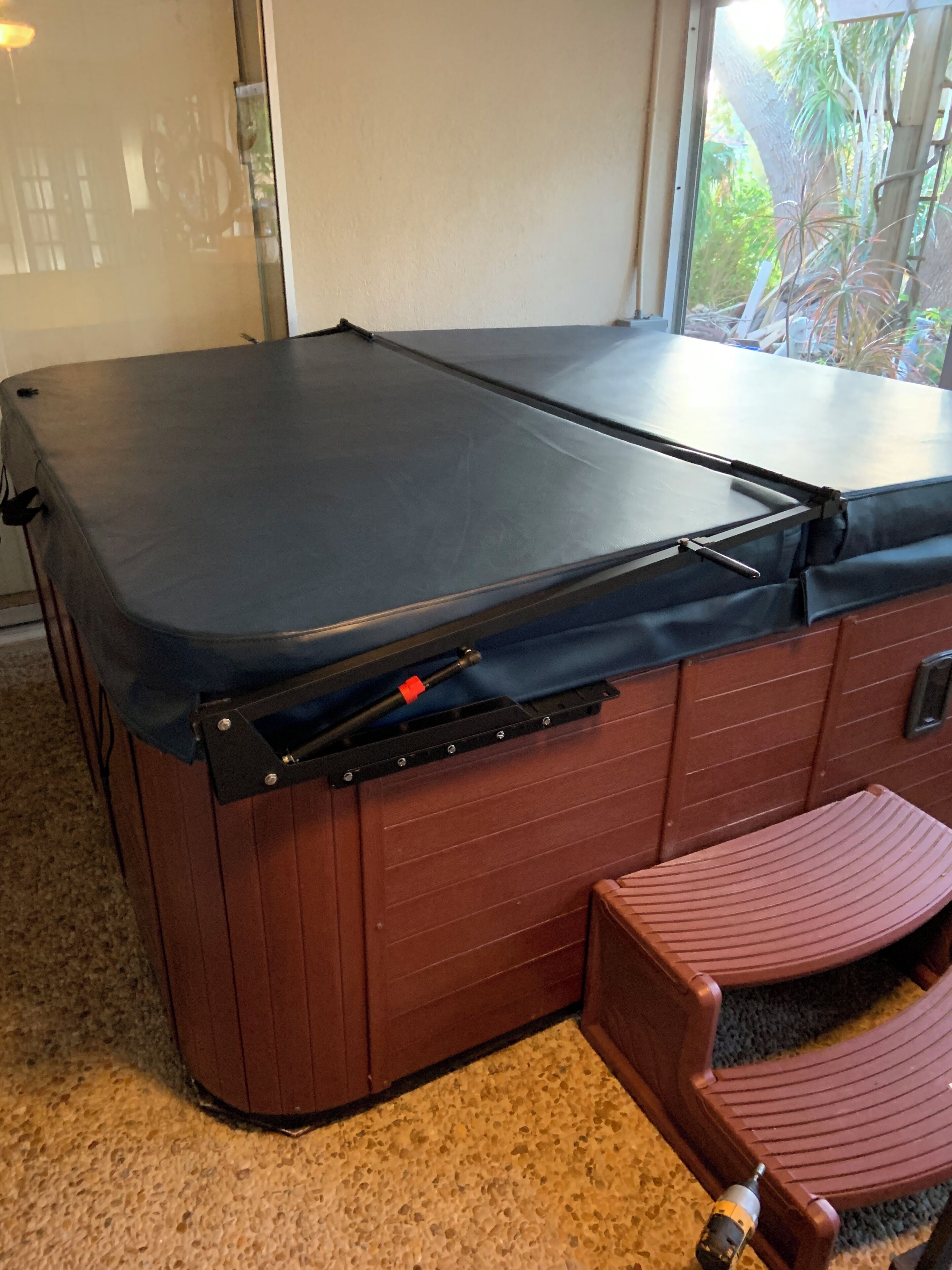 Ein Billardtisch mit blauer Spielvliesdecke, ein roter Holzkasten mit Schubladen und ein kleiner Holzstuhl.