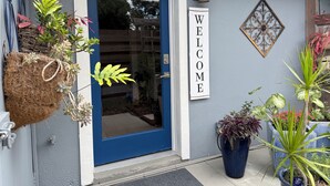 A blue door with a 'WELCOME' sign, a hanging plant, a potted plant, and a decorative wall piece. - Sarasota Cozy & Clean, Near #1 Beach Siesta in SouthGate Neighborhood  (Sarasota)