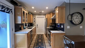 A modern kitchen with wooden cabinets, a built-in oven, and a dining area with a table and chairs. - Sarasota Cozy & Clean, Near #1 Beach Siesta in SouthGate Neighborhood  (Sarasota)