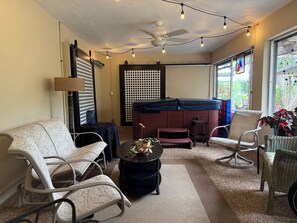 A room with a ceiling fan, string lights, a pool table, and a view of the outdoors.
