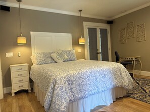 A bedroom with a bed, bedside tables, a desk, and a chair.