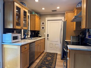 A compact kitchen with wooden cabinets, a microwave, a dishwasher, and a refrigerator.