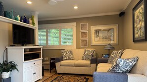 A living room with a sofa, a television, a cabinet, a plant, and a patterned rug. - Sarasota Cozy & Clean, Near #1 Beach Siesta in SouthGate Neighborhood  (Sarasota)