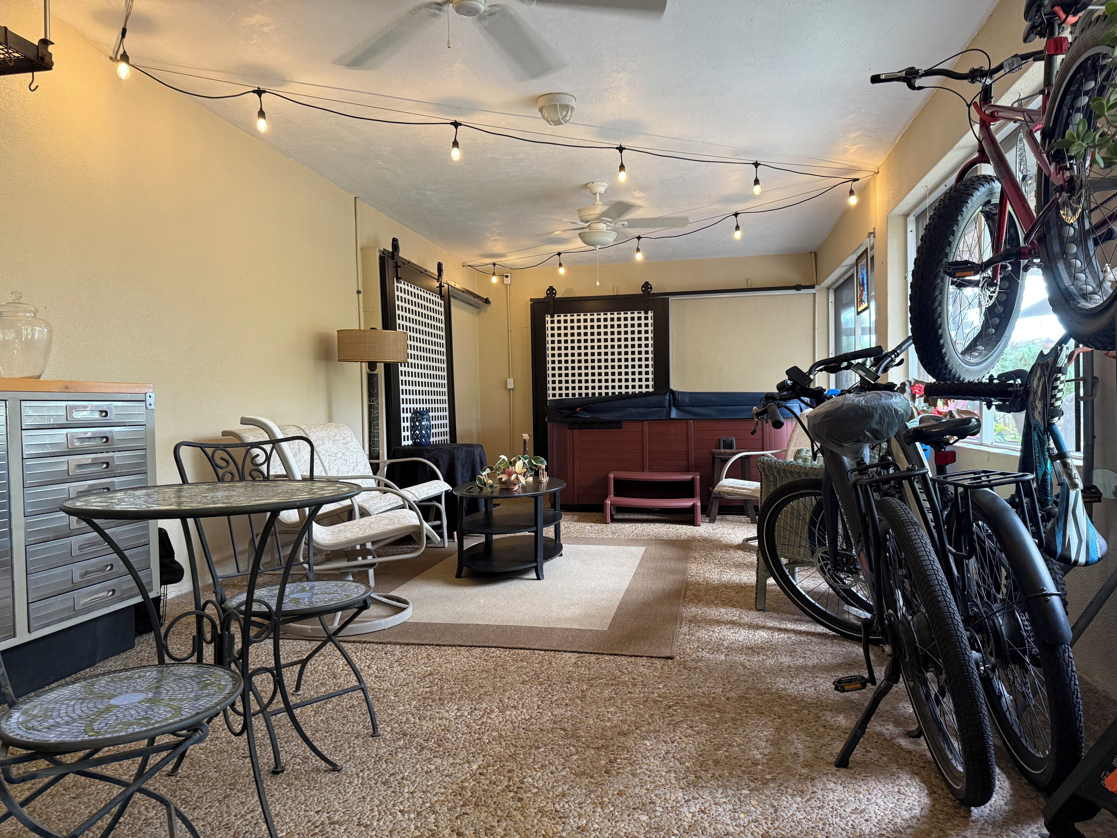 Ein Wohnzimmer mit Deckenventilator, Lichterkette, einem Fahrrad und einer Couch.