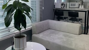 Un salon moderne avec un canapé gris, une table ronde blanche et une plante en pot.