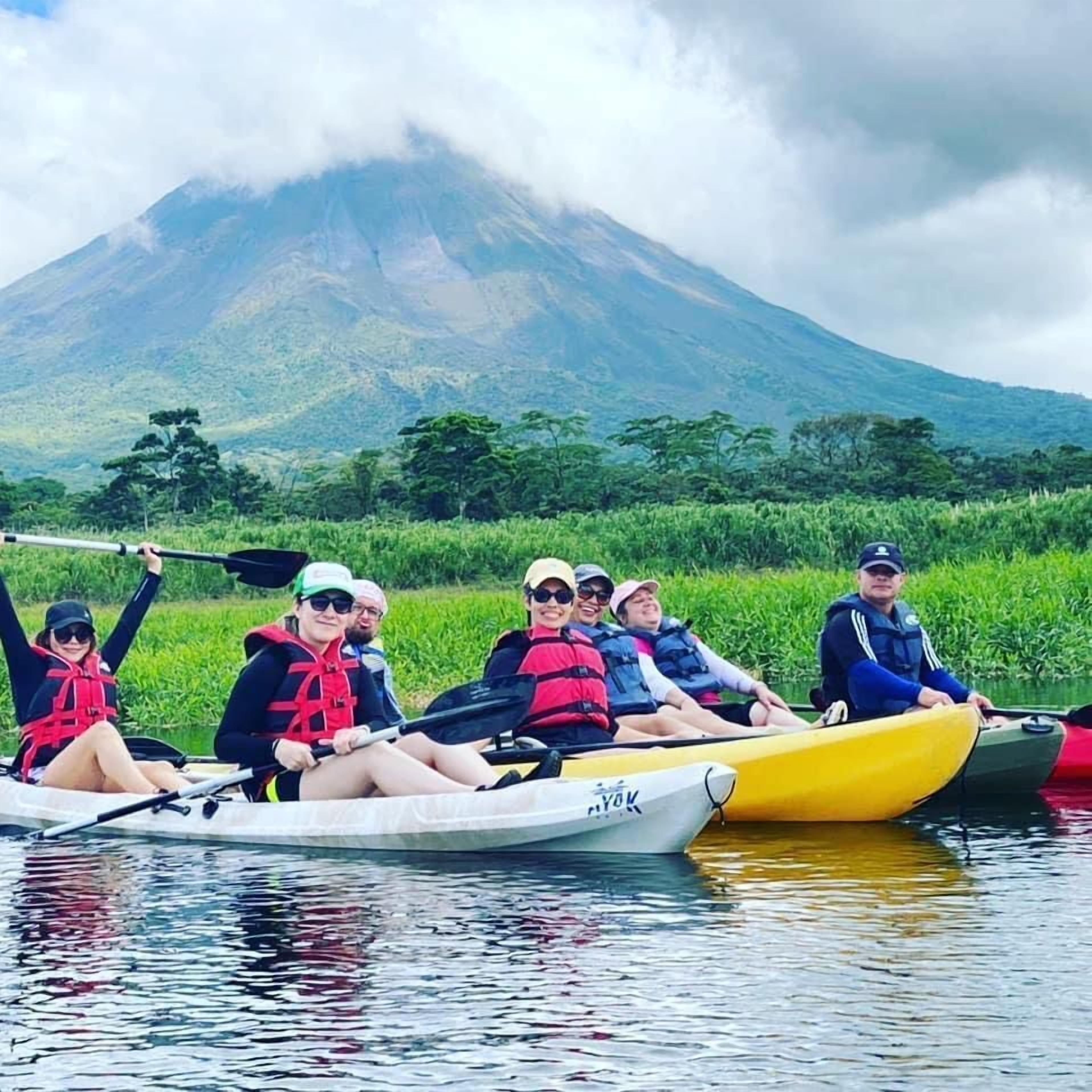 Un groupe de personnes dans un canoë sur une rivière, avec une montagne en arrière-plan.