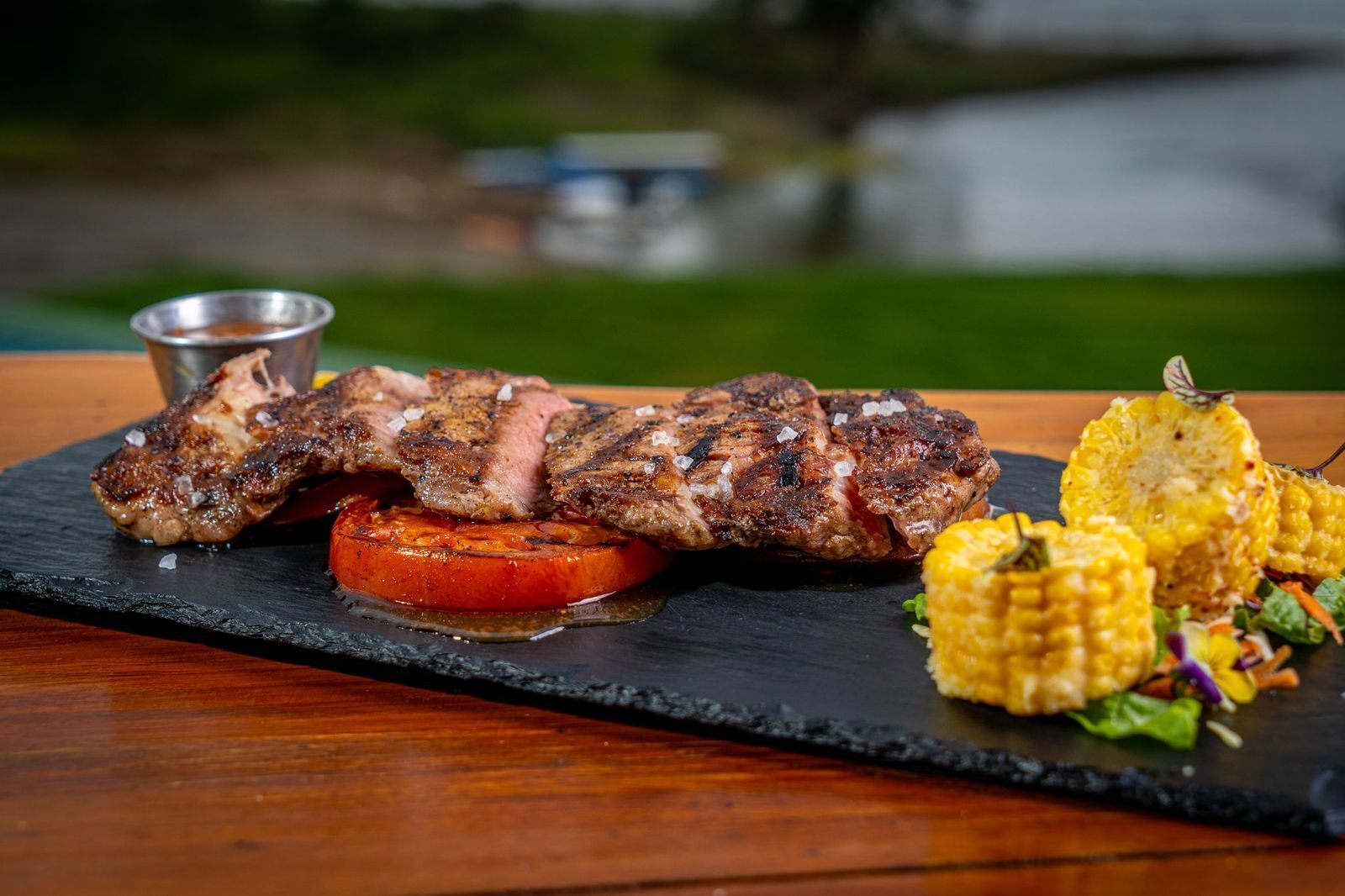 A steak with grilled vegetables on a slate board.