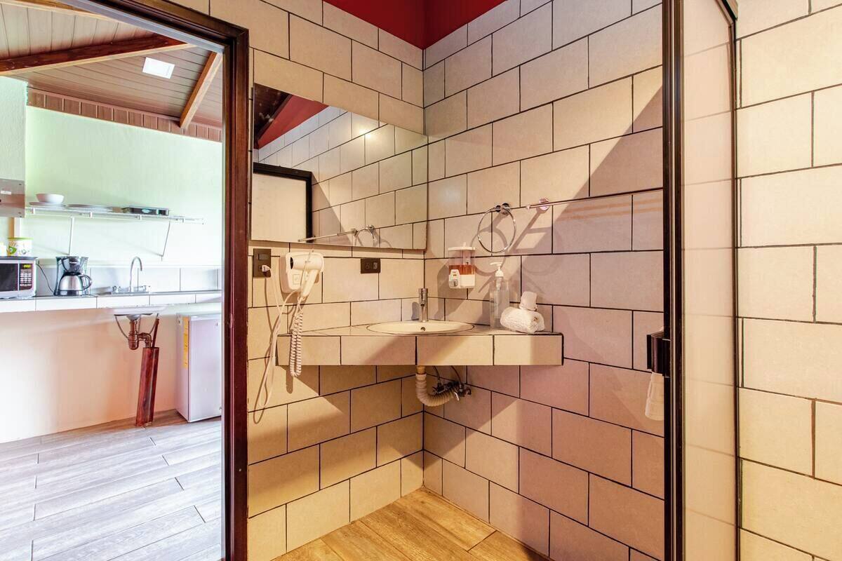 A modern bathroom with a tiled wall, a sink, and a mirror.