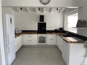 Enjoy cooking in this well-equipped kitchen with a stainless steel oven, black range hood, microwave, coffee maker, and sink.