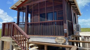 Eine Holzhütte mit Balkon, einem Schild mit der Aufschrift 'Flamingo' und Blick auf den Strand.