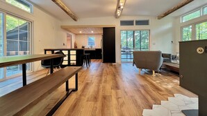Amplia sala de estar con piso de madera, una mesa de comedor, un sofá y una cocina al fondo.