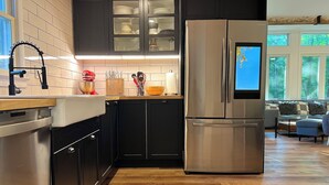 Una cocina moderna con armarios oscuros, electrodomésticos de acero inoxidable y encimera de madera.