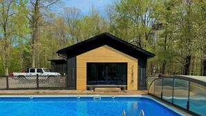 Una piscina con cubierta de madera y un pequeño edificio de madera con techo negro.
