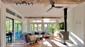 Amplia sala de estar con chimenea, ventanas grandes y ventilador de techo.