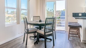 Un coin repas avec une table ronde, quatre chaises et une vue sur l’extérieur, accessible par une porte vitrée.