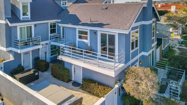 Une maison à deux étages avec un balcon, un petit garage attenant et un jardin bien entretenu.