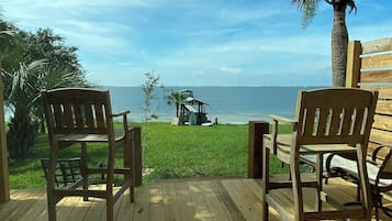 Guests can enjoy serene views of the water from the deck, surrounded by lush greenery and a nearby gazebo.