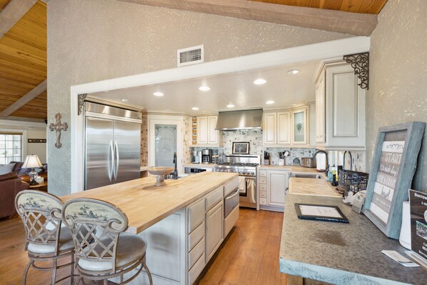 A spacious kitchen with a large island, stainless steel appliances, and a cozy seating area with two chairs. - Temecula Wine Country Home on 5 Acre Vineyard (Temecula)