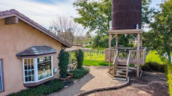 Une maison dotée d’un patio couvert, d’une grande tour cylindrique et, au loin, d’un vignoble.