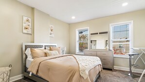 A bedroom with a bed, dresser, and a desk with a chair.