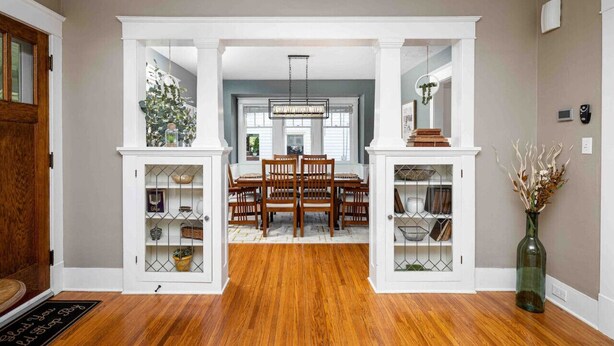 A dining area with a wooden table and chairs, flanked by white cabinets with glass doors. - Walk to Shops & Dining, Great Location! - 3br (Perrysburg)