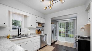 A modern kitchen with white cabinetry, a granite countertop, a stainless steel refrigerator, and a gas stove. - Walk to Shops & Dining, Great Location! - 3br (Perrysburg)