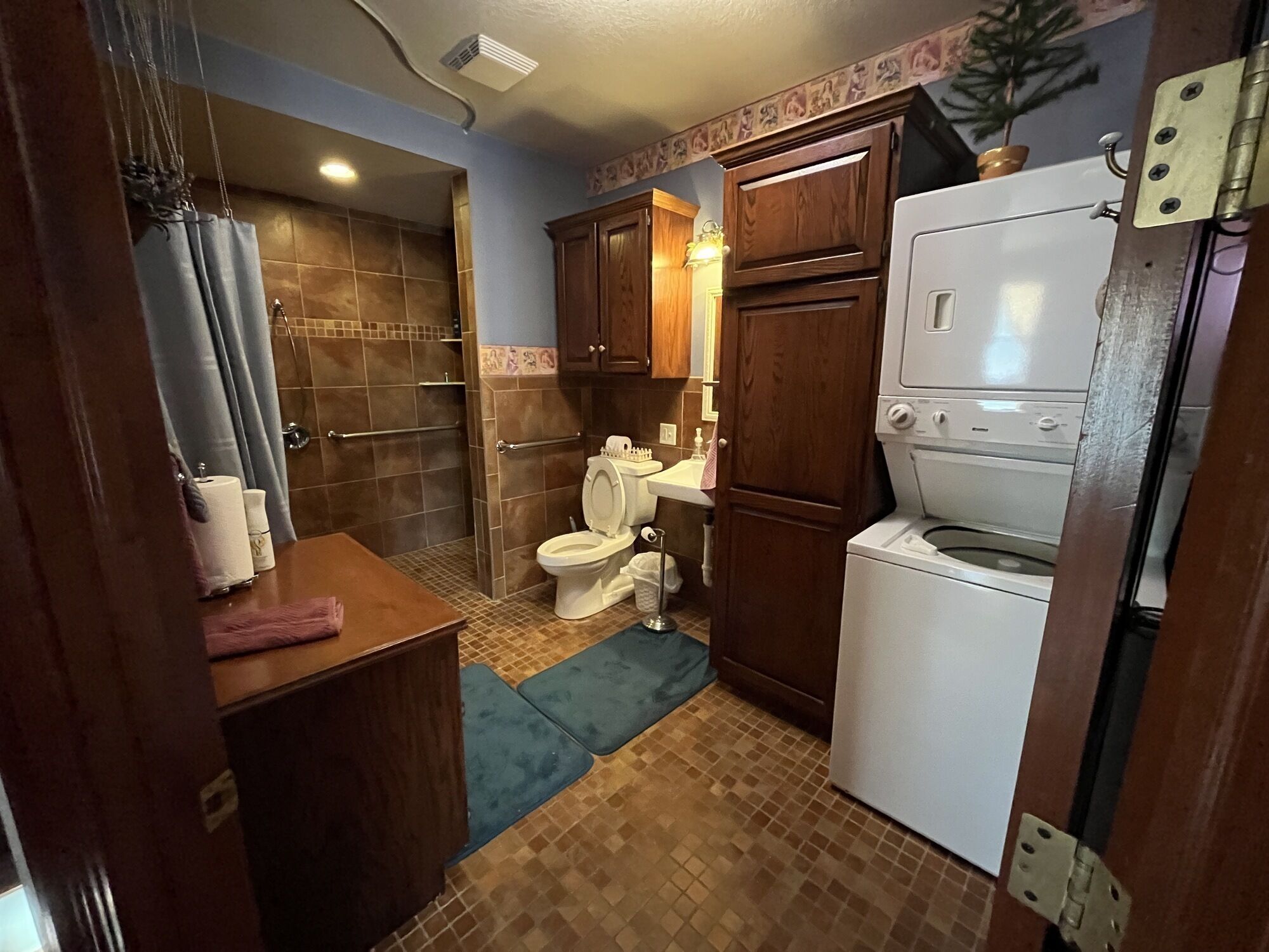 A compact bathroom with a shower, toilet, sink, and a built-in washing machine.