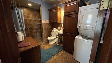 A compact bathroom with a shower, toilet, sink, and a built-in washing machine.