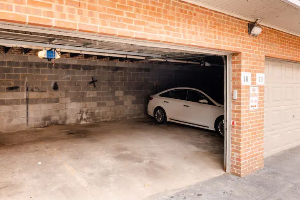 A garage with a white car parked inside, brick walls, and a garage door number 18.