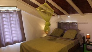 Una camera da letto con un letto, un comodino, una lampada, una finestra con tende e una ventola a soffitto.