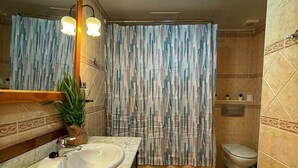 Un baño con lavamanos, espejo, cortina de ducha, inodoro y un tapete verde.