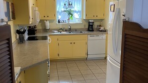 A kitchen with yellow cabinets, a white refrigerator, a ceiling fan, and a window with curtains. - 8 Blocks from Main Street (Fredericksburg)