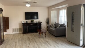 A living room with a flat-screen TV, a fireplace, a sofa, and a dining table. - 8 Blocks from Main Street (Fredericksburg)