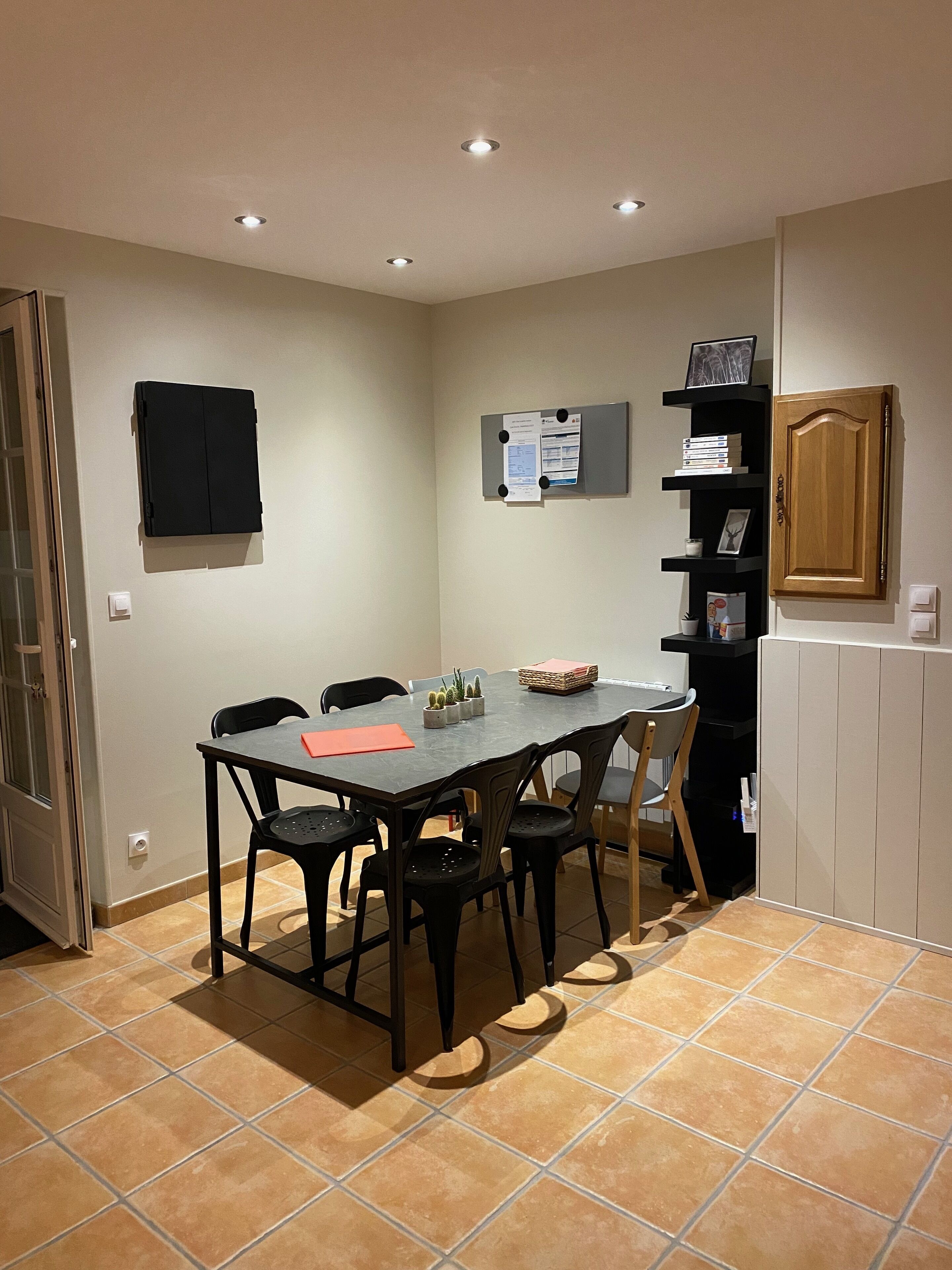 Un comedor con una mesa y sillas, una estantería, un mueble de madera y una puerta.