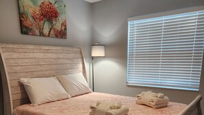 Un dormitorio con una cama de madera, una mesita de noche, una lámpara y una ventana con persianas.