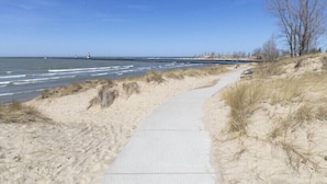 A sandy beach path leading to the ocean with a lighthouse in the distance. - Newly remodeled LAKE HOUSE with HOT TUB, Game Room, Large DECK on PAW PAW LAKE (Coloma)