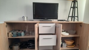 Une petite cuisine équipée avec un téléviseur, une petite machine à café et un tabouret.