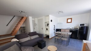 Un appartement moderne comprenant un salon, un coin repas, une cuisine et un escalier.