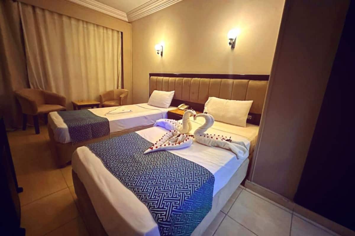 A hotel room with two beds, a sofa, and a desk.