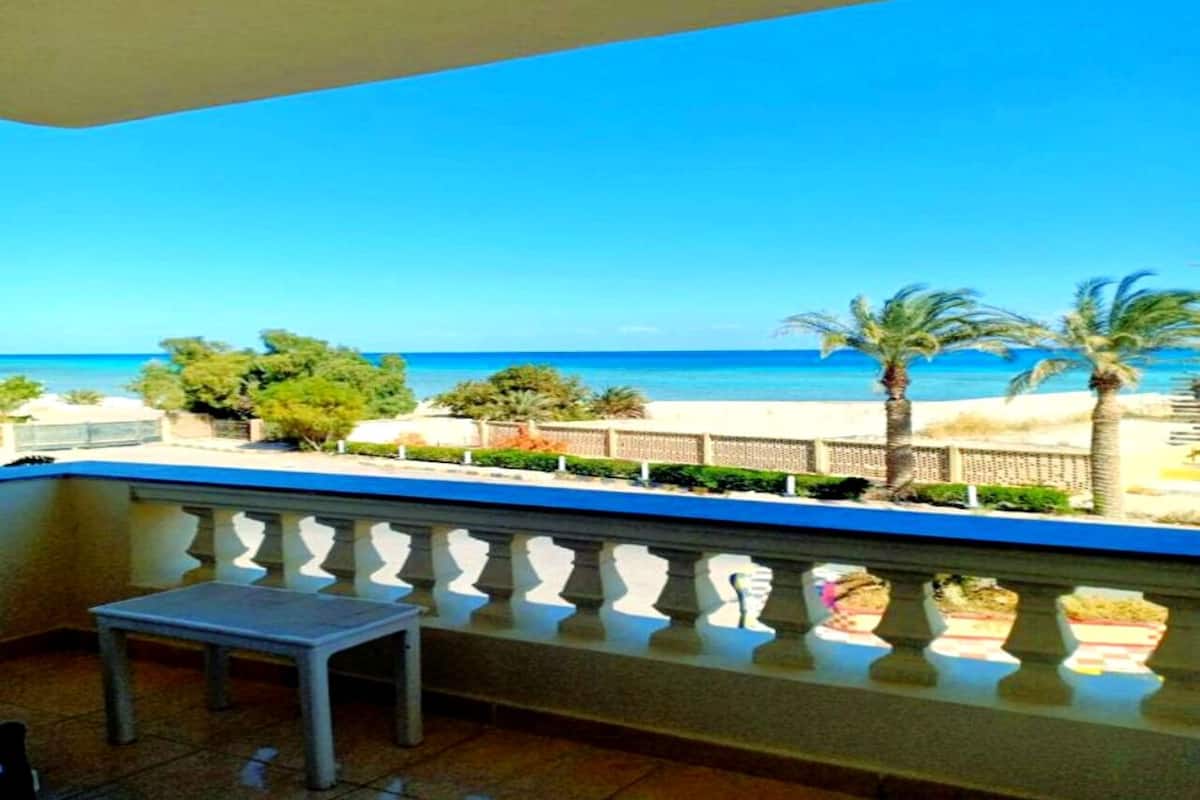 A balcony with a view of the sea, a small table, and decorative vases.