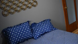 A bedroom with a bed, two blue patterned pillows, a geometric wall decoration, and a wooden door. - Cozy Nothwoods home next to ATV/Snowmobile trails (Laona)