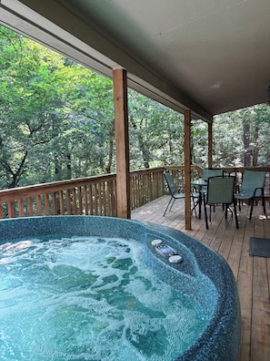 A hot tub on a wooden deck with a view of trees.